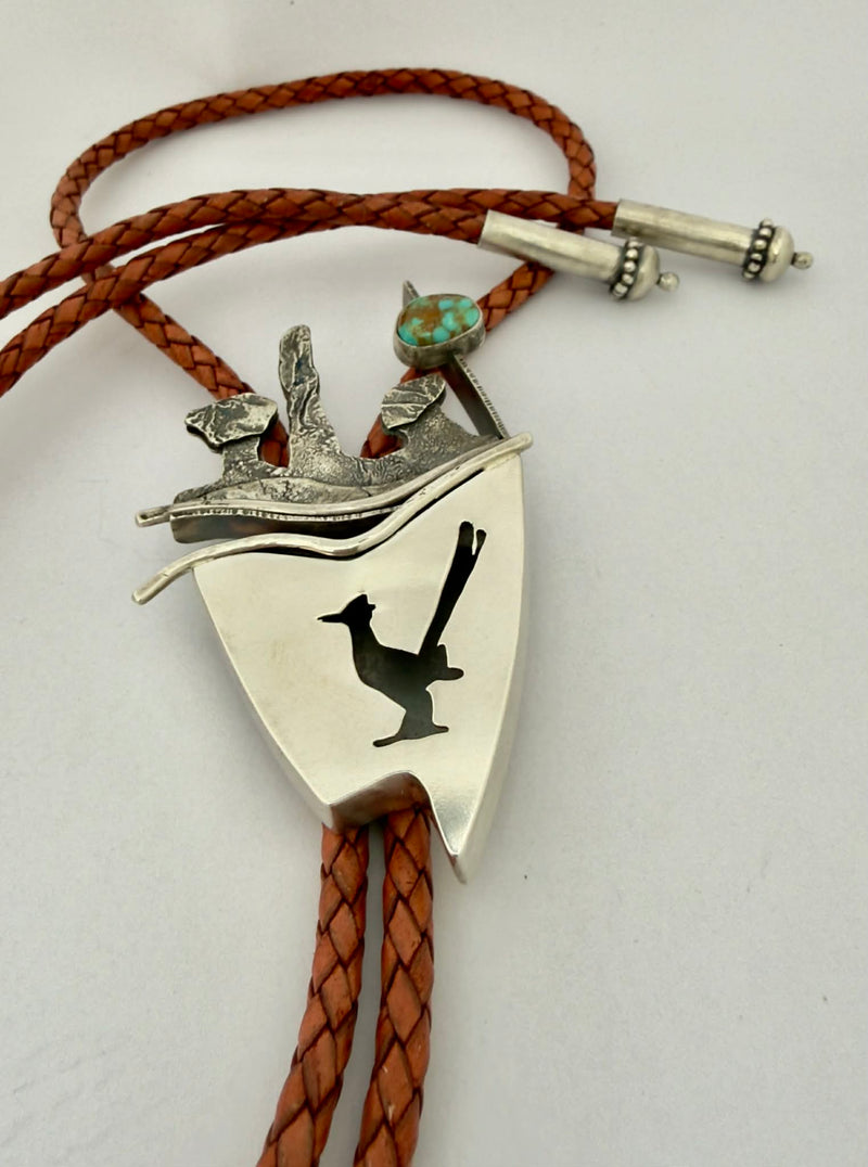 Silver bolo tie with brown leather cord on a white background